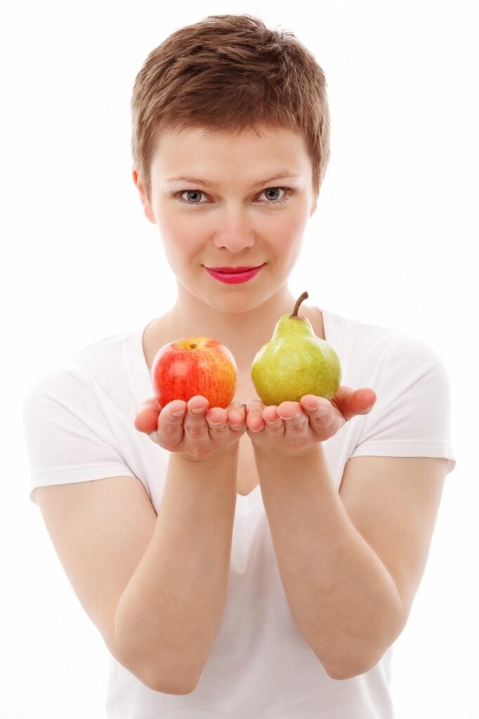Salud Mujer pelo corto con camiseta blanca manga corta con una manzana y una pera en las manos